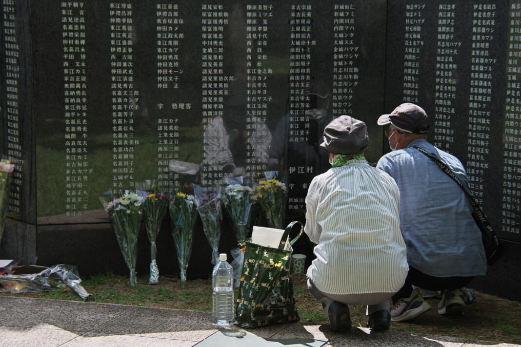 沖縄戦の犠牲者の名前を刻む「平和の礎（いしじ）」の前で手を合わせる人たち＝2025年６月23日午前、沖縄県糸満市
