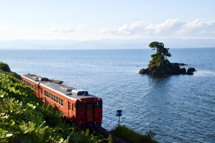 JR氷見線の電車（高岡行き）と雨晴海岸の女岩（富山県高岡市）